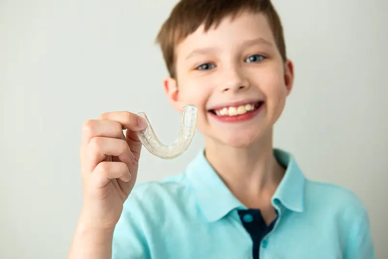 a photo of a young boy holding a transparent orthopedic appliance